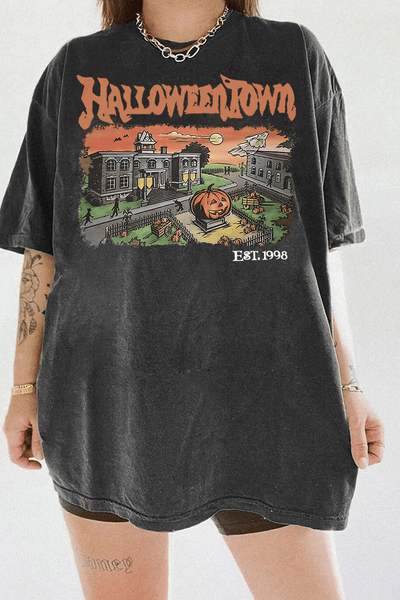Ragglo dark gray women's T-Shirt featuring a spooky town with a jack-o'-lantern, graveyard, and old houses under a sunset sky with bats, and the text 'Halloween Town Est. 1998' in a retro Halloween graphic design.