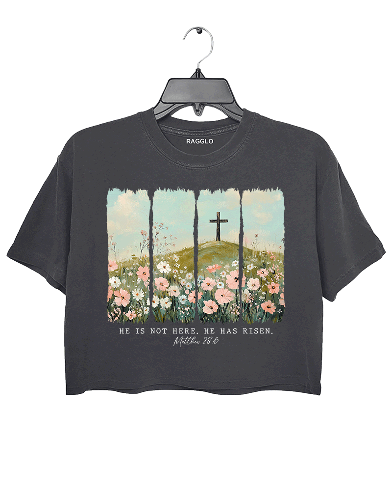 Ragglo dark gray women's crop top with 'He Is Not Here, He Has Risen' text and cross on hill with wildflowers graphic.