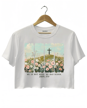 Ragglo white women's crop top with 'He Is Not Here, He Has Risen' text and cross on hill with wildflowers graphic.

