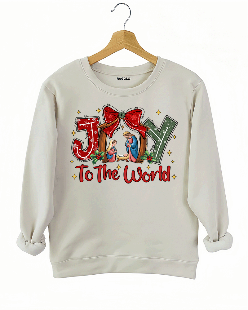 Ragglo beige sweatshirt featuring 'JOY TO THE WORLD' text with a nativity scene, a red bow, and holly leaves, perfect for religious Christmas streetwear and festive celebrations.








