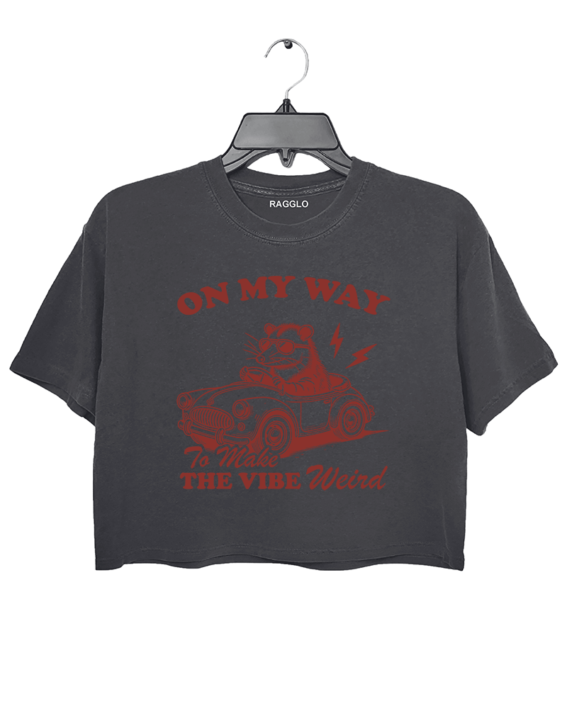 Ragglo dark gray women's crop top with 'On My Way to Make the Vibe Weird' text and raccoon driving car graphic.

