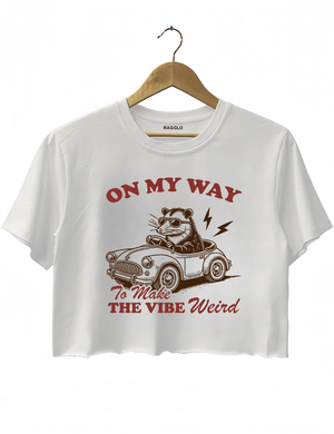 Ragglo white women's crop top with 'On My Way to Make the Vibe Weird' text and raccoon driving car graphic.

