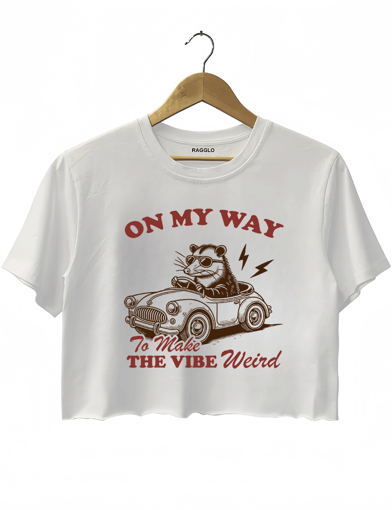 Ragglo white women's crop top with 'On My Way to Make the Vibe Weird' text and raccoon driving car graphic.

