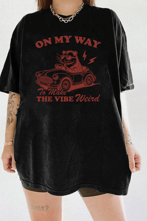 Ragglo black women's t-shirt with 'On My Way to Make the Vibe Weird' text and raccoon driving car graphic.

