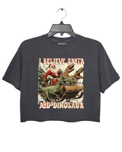 Ragglo dark gray women's crop top with 'I Believe Santa and Dinosaur' text and Santa sleigh pulled by dinosaurs graphic.

