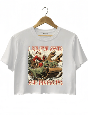 Ragglo white women's crop top with 'I Believe Santa and Dinosaur' text and Santa sleigh pulled by dinosaurs graphic.

