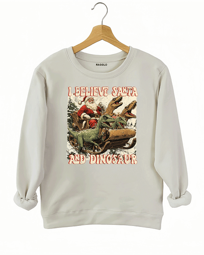 Ragglo beige women's sweatshirt with 'I Believe Santa and Dinosaur' text and Santa sleigh pulled by dinosaurs graphic.

