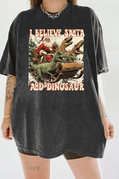 Ragglo dark gray women's tee with 'I Believe Santa and Dinosaur' text and Santa sleigh pulled by dinosaurs graphic.

