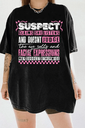 Black Ragglo women's t-shirt with pink 'Suspect' design, featuring playful text: 'Claims she listens and doesn't judge, the eye rolls and facial expressions may suggest otherwise.

