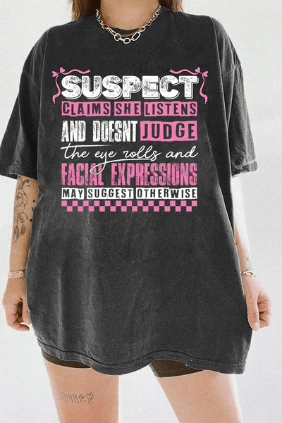 Dark Gray Ragglo women's t-shirt with pink 'Suspect' design, featuring playful text: 'Claims she listens and doesn't judge, the eye rolls and facial expressions may suggest otherwise.


