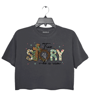 Dark gray Ragglo women's crop t-shirt with 'True Story He Is Risen' text, featuring a cross with a crown of thorns and floral design, ideal for Easter and Christian faith celebrations.


