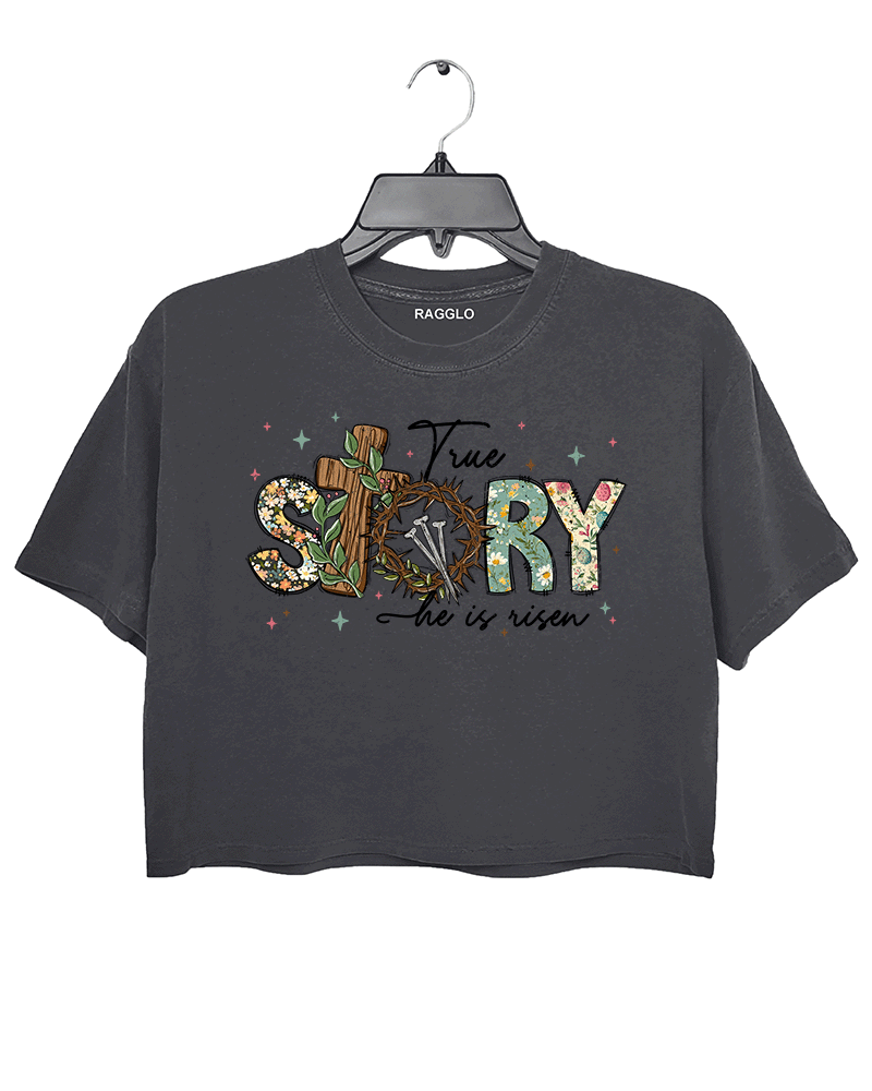 Dark gray Ragglo women's crop t-shirt with 'True Story He Is Risen' text, featuring a cross with a crown of thorns and floral design, ideal for Easter and Christian faith celebrations.

