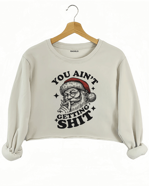 Cozy beige Ragglo women's crop sweatshirt featuring a Santa Claus graphic with the text "YOU AIN'T GETTING SHIT" in bold black, hanging on a wooden hanger.


