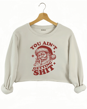 Cozy beige Ragglo women's crop sweatshirt featuring a Santa Claus graphic with the text "YOU AIN'T GETTING SHIT" in bold red, hanging on a wooden hanger.

