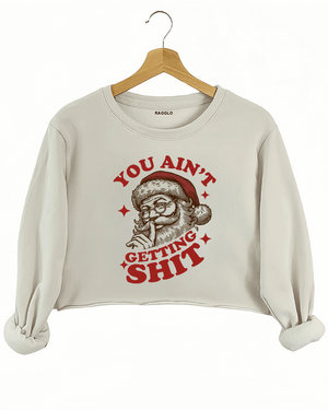 Cozy beige Ragglo women's crop sweatshirt featuring a Santa Claus graphic with the text "YOU AIN'T GETTING SHIT" in bold red and brown, hanging on a wooden hanger.

