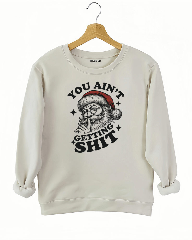 Beige Ragglo women's sweatshirt made of soft fleece, featuring a Santa Claus graphic with the text "YOU AIN'T GETTING SHIT" in black, hanging on a wooden hanger.

