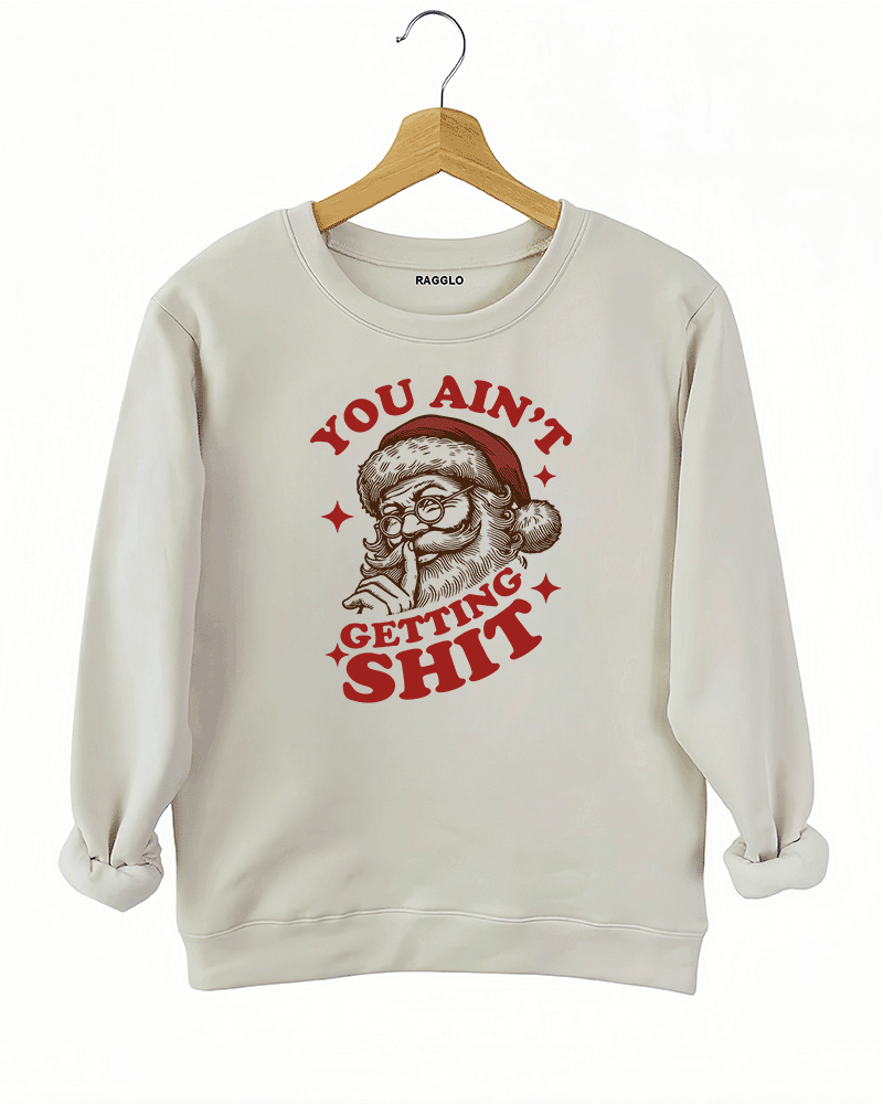 Beige Ragglo women's sweatshirt made of soft fleece, featuring a Santa Claus graphic with the text "YOU AIN'T GETTING SHIT" in red and brown, hanging on a wooden hanger.

