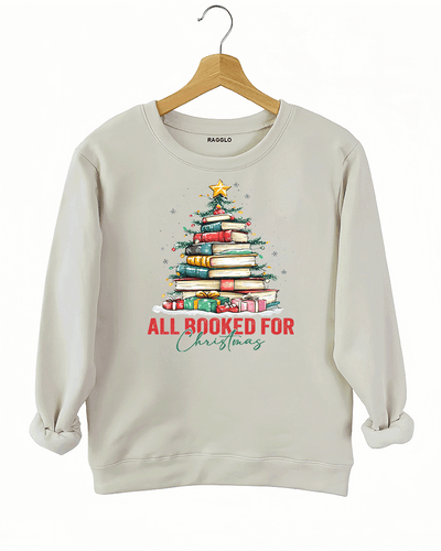 Ragglo beige sweatshirt featuring a Christmas tree made of stacked books, decorated with lights, stars, and gifts, with 'ALL BOOKED FOR CHRISTMAS' text, perfect for festive streetwear for book lovers.

