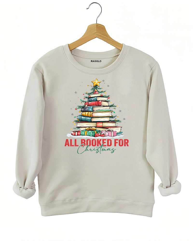 Ragglo beige sweatshirt featuring a Christmas tree made of stacked books, decorated with lights, stars, and gifts, with 'ALL BOOKED FOR CHRISTMAS' text, perfect for festive streetwear for book lovers.

