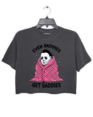 Ragglo dark gray crop top featuring Michael Myers wrapped in a pink blanket with stars, with 'EVEN BADDIES GET SADDIES' text, perfect for horror movie fans and mental health awareness streetwear.

