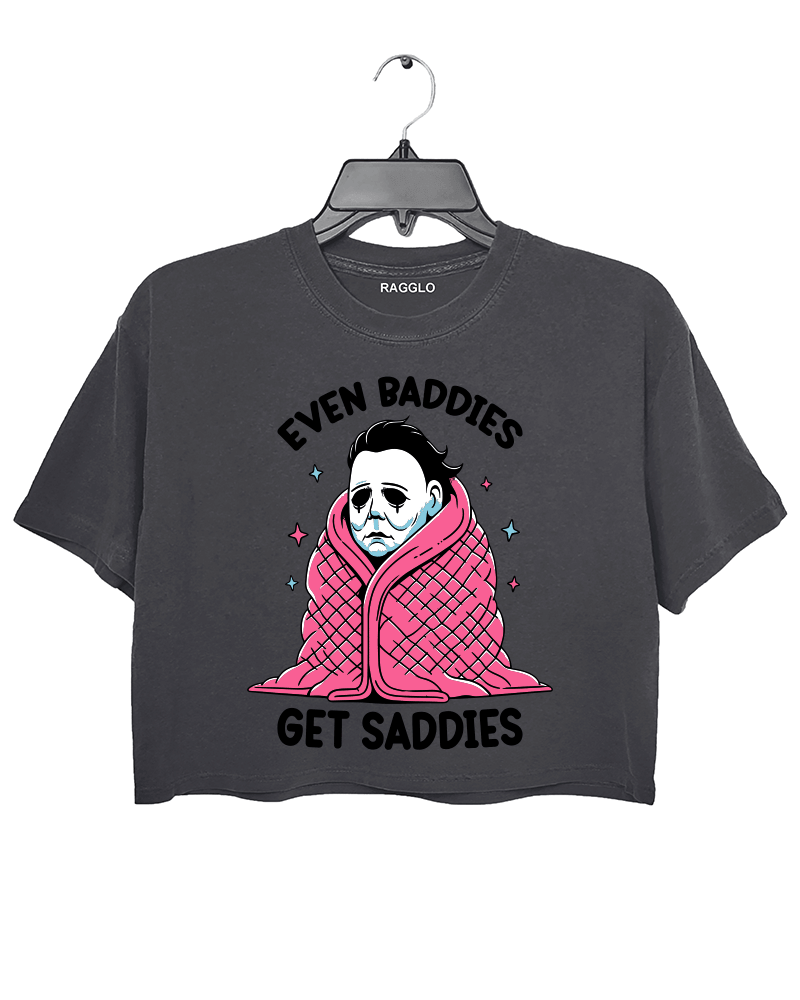 Ragglo dark gray crop top featuring Michael Myers wrapped in a pink blanket with stars, with 'EVEN BADDIES GET SADDIES' text, perfect for horror movie fans and mental health awareness streetwear.

