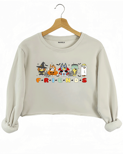 Ragglo beige crop sweatshirt featuring five Bluey characters in Halloween costumes as a witch, vampire, Frankenstein, construction worker, and ghost, with 'F·R·I·E·N·D·S' text in a Friends-inspired font, perfect for cute Halloween streetwear for animation fans.

