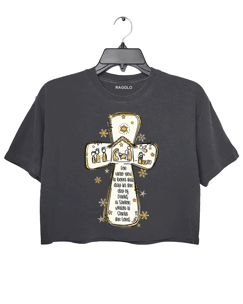 Ragglo dark gray crop top featuring a cross with a nativity scene, stars, and snowflakes, with 'Unto you is born this day in the city of David, a Savior which is Christ the Lord' text, perfect for religious Christmas streetwear.

