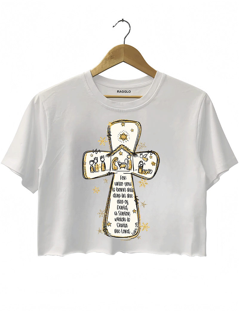 Ragglo white crop top featuring a cross with a nativity scene, stars, and snowflakes, with 'Unto you is born this day in the city of David, a Savior which is Christ the Lord' text, perfect for religious Christmas streetwear.

