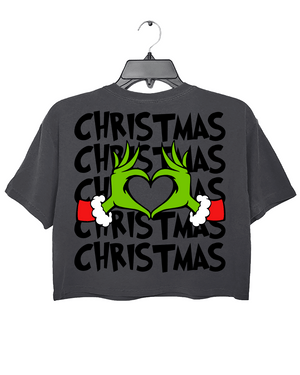 Ragglo dark gray women's crop top back featuring larger Grinch hands making a heart shape with Santa cuffs, surrounded by the repeated text 'Christmas' in a humorous holiday graphic design.