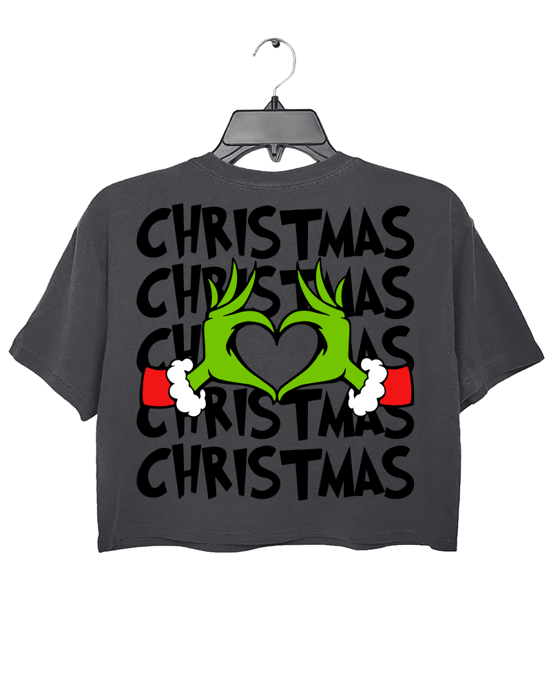 Ragglo dark gray women's crop top back featuring larger Grinch hands making a heart shape with Santa cuffs, surrounded by the repeated text 'Christmas' in a humorous holiday graphic design.