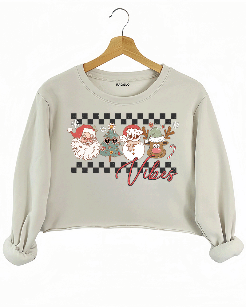 Ragglo beige crop sweatshirt with "Vibes" text and Christmas graphic featuring Santa, snowman, and reindeer, showcasing a festive holiday theme with a checkered background.

