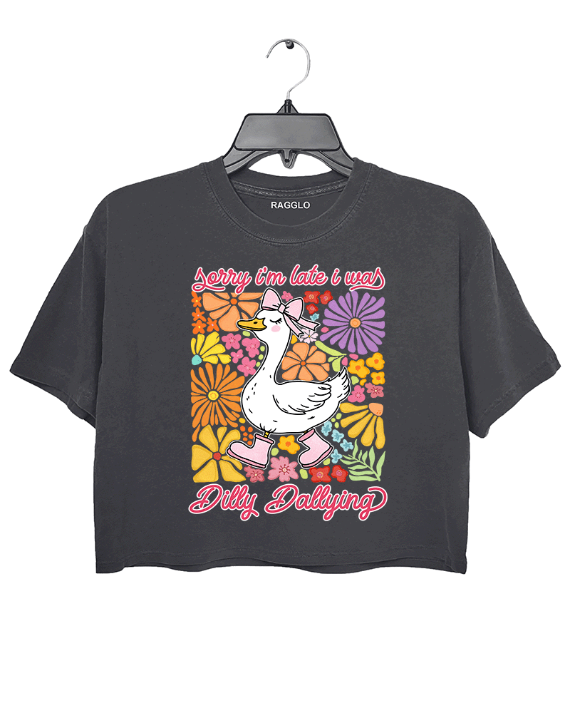 Ragglo dark gray crop top featuring a cute duck in pink rain boots and a bow, surrounded by vibrant flowers, with 'Sorry I'm Late I Was Dilly Dallying' text, perfect for playful floral-inspired casual wear.

