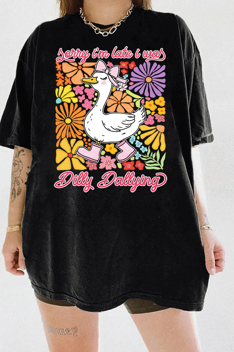 Ragglo black tee featuring a cute duck in pink rain boots and a bow, surrounded by vibrant flowers, with 'Sorry I'm Late I Was Dilly Dallying' text, perfect for playful floral-inspired casual wear.

