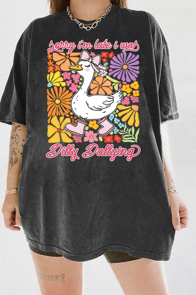 Ragglo dark gray tee featuring a cute duck in pink rain boots and a bow, surrounded by vibrant flowers, with 'Sorry I'm Late I Was Dilly Dallying' text, perfect for playful floral-inspired casual wear.

