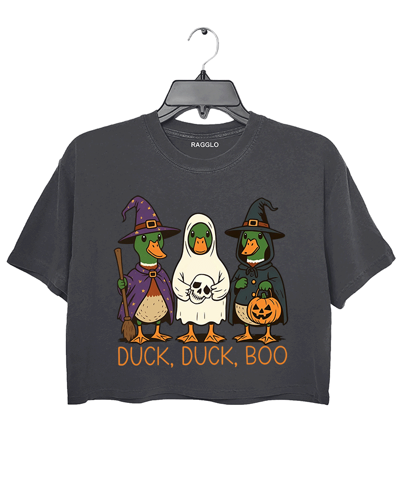 Dark gray crop top featuring three cute ducks dressed in Halloween costumes: a purple wizard, a ghost in a white sheet, and a witch with a pumpkin lantern. The text 'DUCK, DUCK, BOO' is printed below the characters in orange.