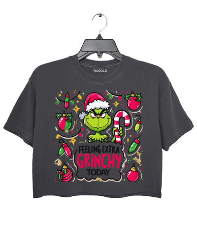 Ragglo dark gray crop top featuring the Grinch in a Santa hat, surrounded by candy canes, lights, and ornaments, with 'FEELING EXTRA GRINCHY TODAY' text, perfect for funny Christmas streetwear.


