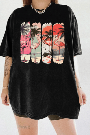 Ragglo black tee featuring four pink flamingos on a beach with palm trees and a vibrant sunset, perfect for tropical-inspired casual wear.

