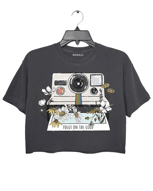 Ragglo dark gray crop top featuring a vintage Polaroid camera surrounded by flowers, with 'FOCUS ON THE GOOD' text, perfect for retro-inspired streetwear with a positive vibe.


