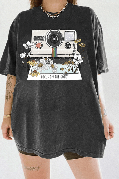 Ragglo dark gray tee featuring a vintage Polaroid camera surrounded by flowers, with 'FOCUS ON THE GOOD' text, perfect for retro-inspired streetwear with a positive vibe.

