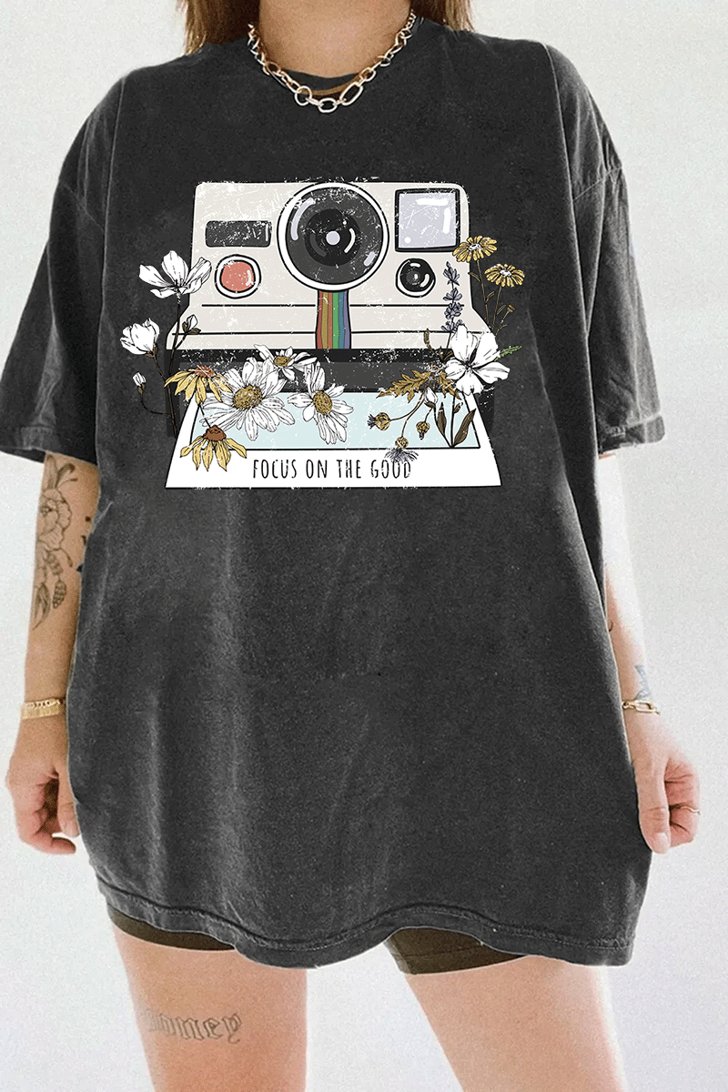 Ragglo dark gray tee featuring a vintage Polaroid camera surrounded by flowers, with 'FOCUS ON THE GOOD' text, perfect for retro-inspired streetwear with a positive vibe.

