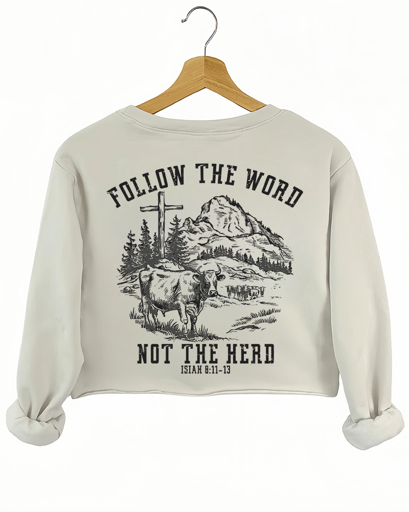 Ragglo beige women's crop sweatshirt back featuring a mountain landscape with cattle, a cross, and trees, and the text 'Follow The Word Not The Herd' and 'Isaiah 8:11-13' in a spiritual graphic design.