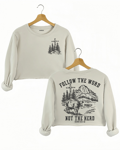 Ragglo beige women's crop sweatshirt featuring a minimalist cross and trees design on the front, and a mountain landscape with cattle, a cross, and trees on the back with the text 'Follow The Word Not The Herd' and 'Isaiah 8:11-13' in a faith-inspired graphic design.