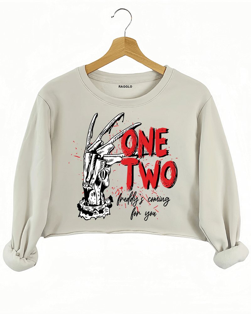 Ragglo beige crop sweatshirt with Freddy Krueger claw graphic and "One Two Freddy's Coming For You" text, inspired by A Nightmare on Elm Street horror theme.

