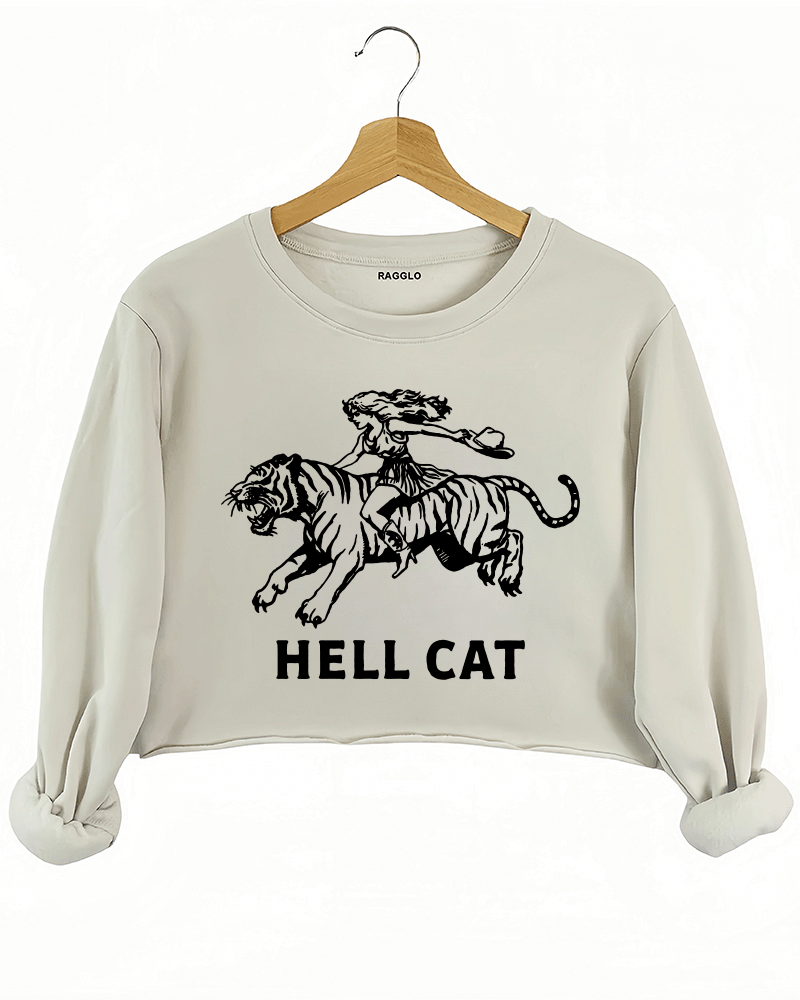 Ragglo beige crop sweatshirt featuring 'HELL CAT' text in black with a graphic of a woman riding a tiger, perfect for bold streetwear and fierce, rebellious vibes.





