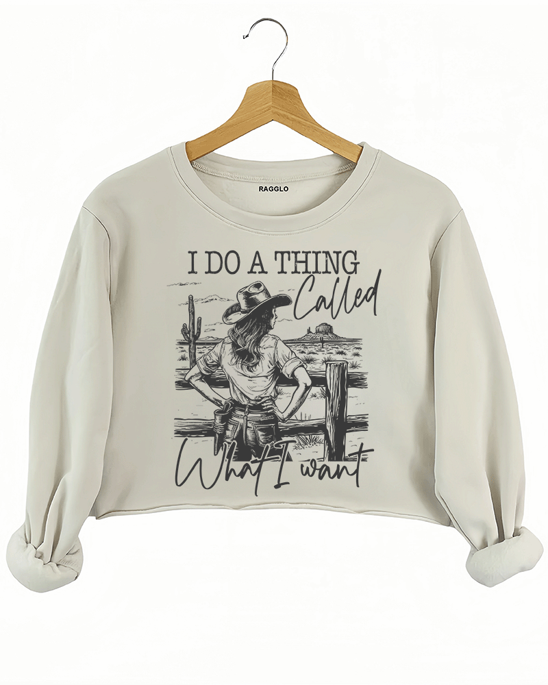 Ragglo beige crop sweatshirt with "I Do A Thing Called What I Want" text and cowgirl graphic in a desert scene, featuring a bold western independence theme.

