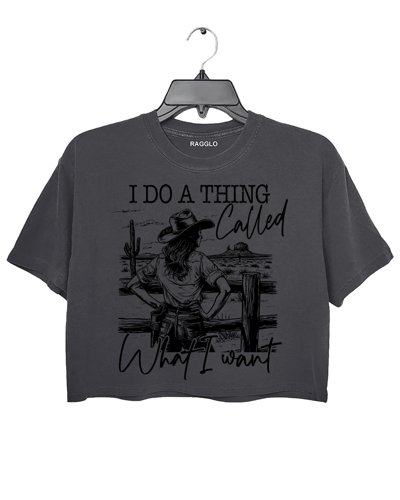 Ragglo dark gray crop top with "I Do A Thing Called What I Want" text and cowgirl graphic in a desert scene, featuring a bold western independence theme.

