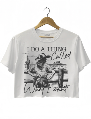 Ragglo white crop top with "I Do A Thing Called What I Want" text and cowgirl graphic in a desert scene, featuring a bold western independence theme.

