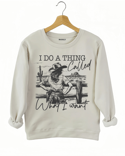 Ragglo beige sweatshirt with "I Do A Thing Called What I Want" text and cowgirl graphic in a desert scene, featuring a bold western independence theme.

