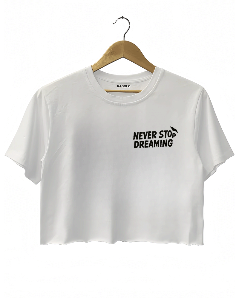 White crop top with the text 'NEVER STOP DREAMING' in bold black font on the left chest.