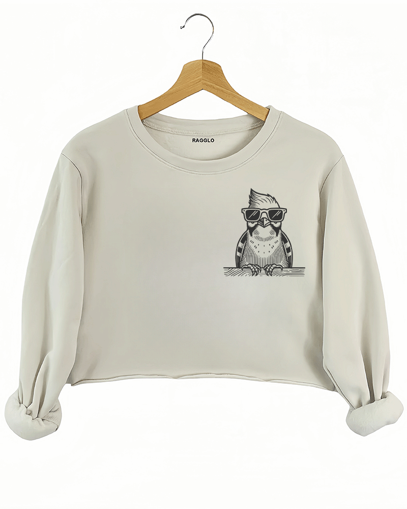 Ragglo beige crop sweatshirt front view showcasing a cool bird with sunglasses and a beard leaning on a ledge, perfect for humorous and trendy streetwear fashion.


